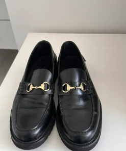 Vinny’s sorte loafers med guld spænde